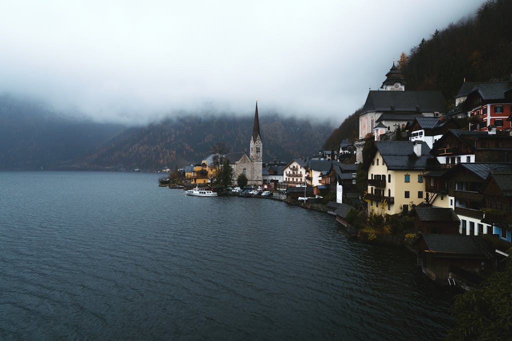 A serene, foggy morning in Hallstatt, Austria, showcasing calm waters and historic architecture.