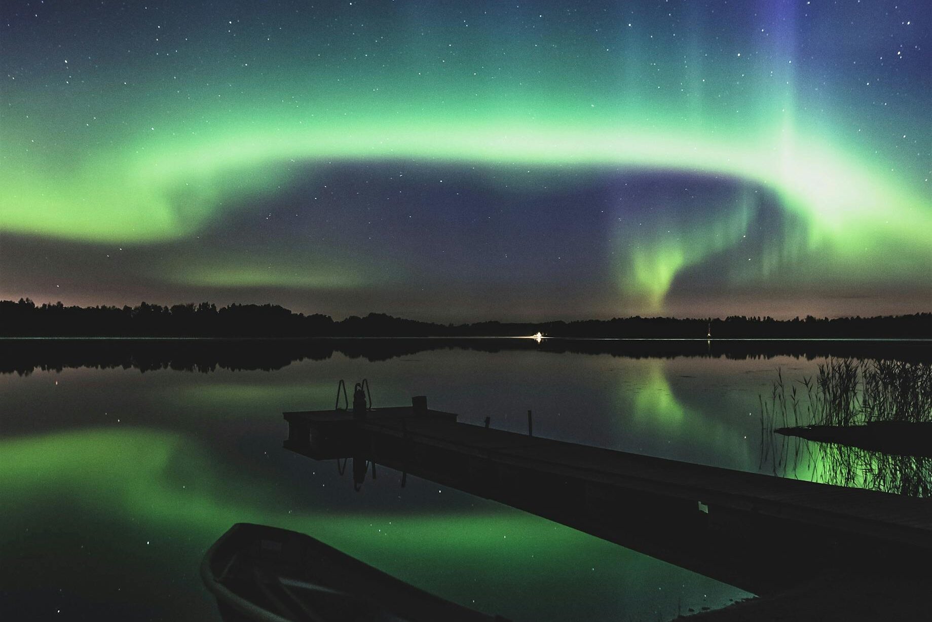 Captivating view of the Northern Lights reflecting over a tranquil lake in Finland.