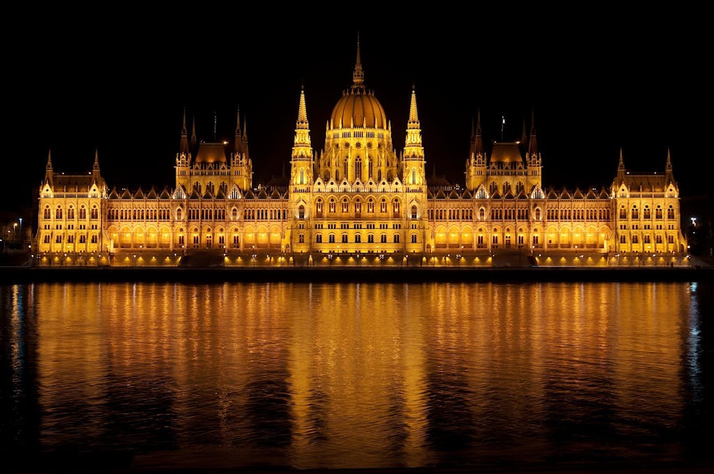 Illuminated view of the Hungarian Parliament Building reflecting in the Danube at night.